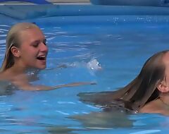 Two beautiful girls swimming and licking by the pool